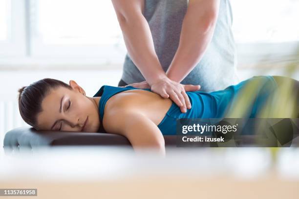 physiotherapist massaging young woman - massage table imagens e fotografias de stock