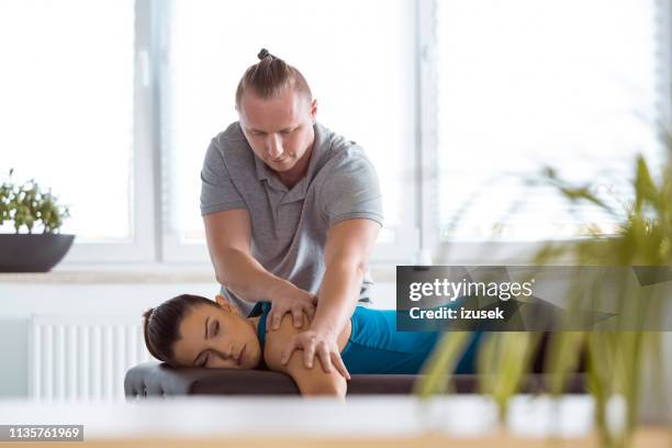 physiothérapeute massant le dos de la jeune femme - male male massage photos et images de collection