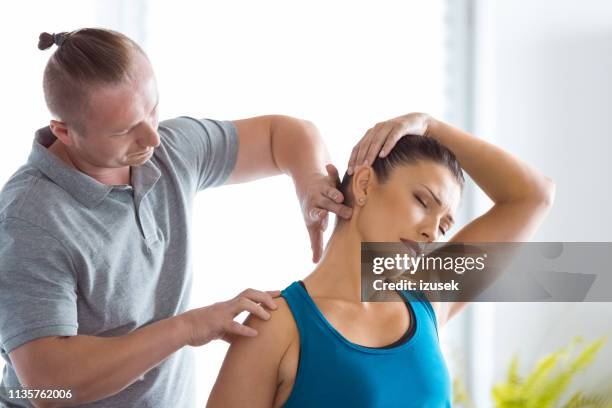 physiotherapist massaging young woman's neck - chiropractic stock pictures, royalty-free photos & images