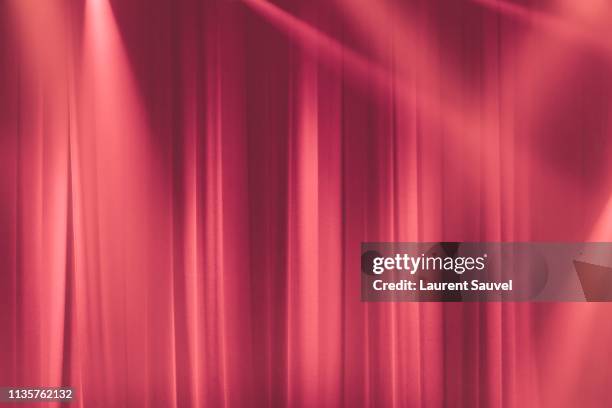 pink stage curtain in the spotlights with light rays - rideau de scène photos et images de collection