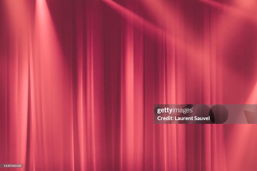 Pink stage curtain in the spotlights with light rays