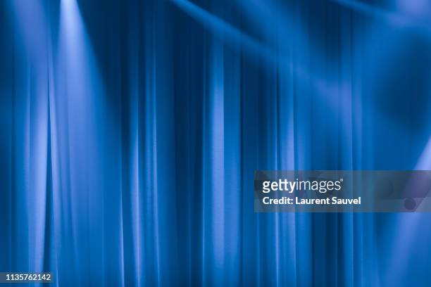 blue stage curtain in the spotlights with light rays - velvet stockfoto's en -beelden