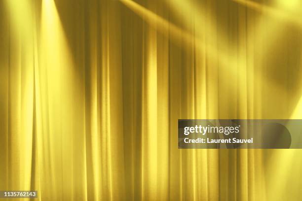 yellow stage curtain in the spotlights with light rays - star background stock-fotos und bilder