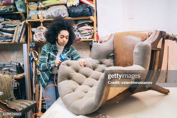 afro female refurbishing chair in upholstery workshop - upholstered furniture stock pictures, royalty-free photos & images