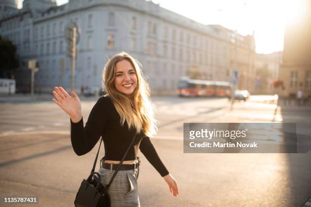 cheerful woman waving at camera as she passes by - waving hand stock-fotos und bilder