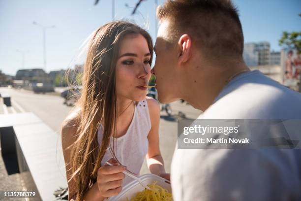 couple slurping a noodle strand until they kiss - noodles eating stock pictures, royalty-free photos & images