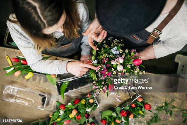 aerial view of two florists preparing bouquet - blumengeschäft stock-fotos und bilder