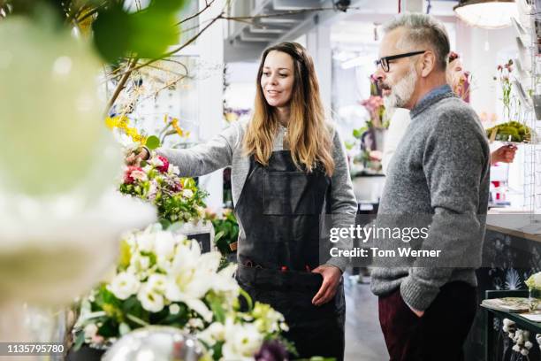 florist helping a customer chose some flowers - florest stock pictures, royalty-free photos & images