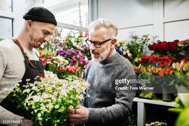 florist assisting customer with bouquet - man flower shirt fotografías e imágenes de stock