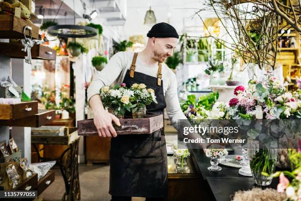 florist arranging his shop display - retail occupation stock-fotos und bilder