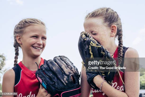 young softball players laughing together on field - girls softball stock pictures, royalty-free photos & images