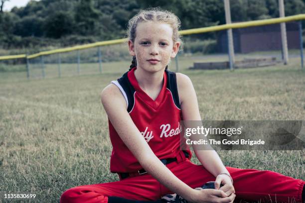 Portrait of girl sitting on softball field
