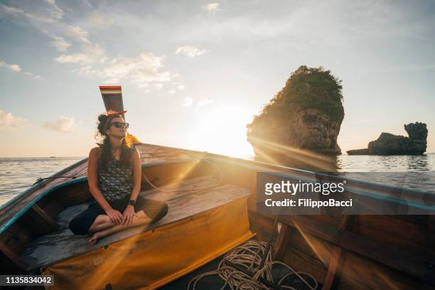 junge frau auf einem longtail-boot in thailand bei sonnenuntergang, phi phi island - thai ethnicity stock-fotos und bilder