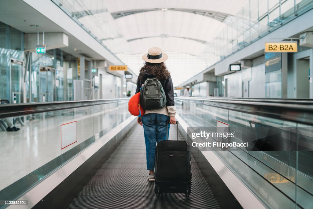 Mujer joven en el aeropuerto con una maleta