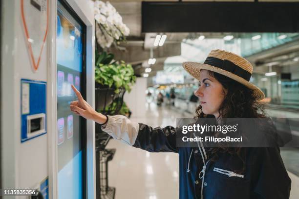 mulher nova que olha uma tela da informação no aeroporto - monitor tátil - fotografias e filmes do acervo