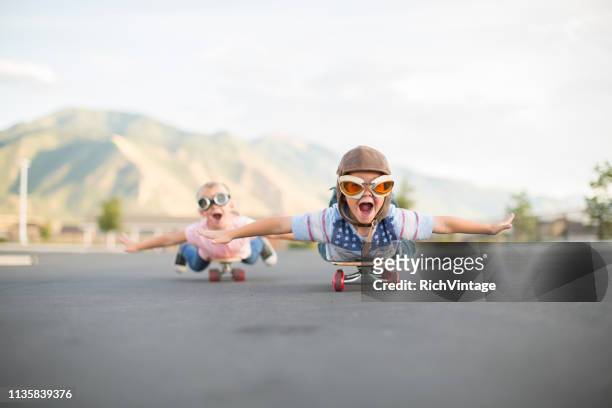 jeune garçon et fille volant sur des planches à roulettes - courage photos et images de collection