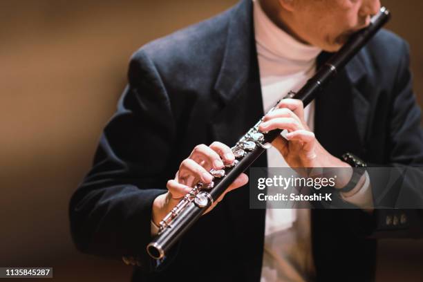 gentleman playing flute in classical music concert - wind instrument stock pictures, royalty-free photos & images