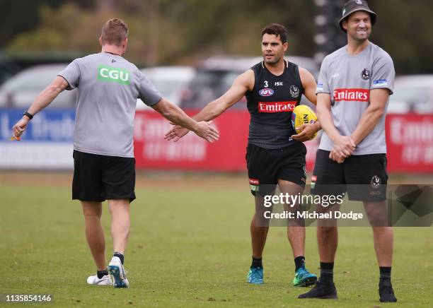 Magpies head coach Nathan Buckley slaps hands with Daniel Wells of the Magpies during the Collingwood Magpies Training Session on March 15, 2019 in...