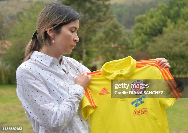 Physiotherapist Carolina Rozo, former physio of the Colombian under-17 national football team, shows a jersey of the team during an interview to AFP...