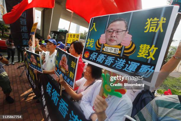 Opponents of the so-called "Umbrella Nine" democracy activists hold placards outside a district court ahead of their verdicts being delivered in Hong...
