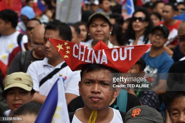 Anti-China protesters raise placards and national flags during a protest in front of Chinese consular office in the financial district of Manila on...
