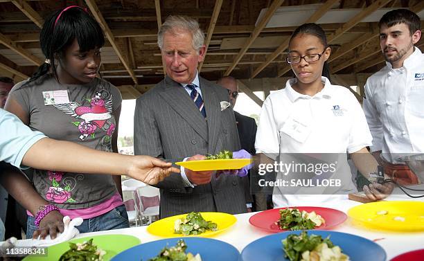 Prince Charles of Wales holds a plate of salad grown at the Common Good City Farm in Washington, DC, May 3 as he tours the farm alongside local area...