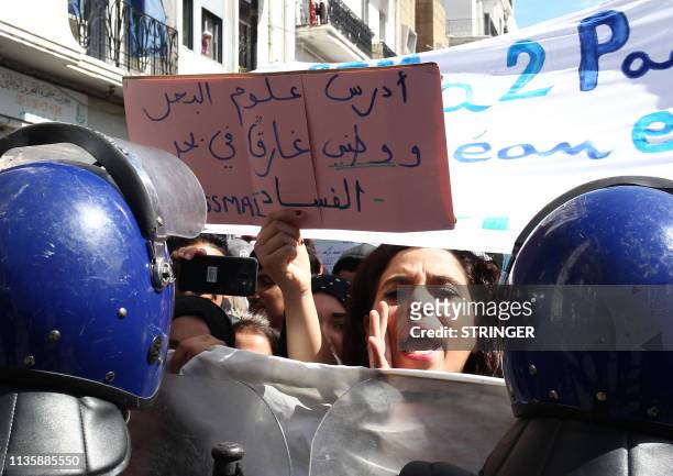 Algerian students carry placards as they take part in an anti-government demonstration in the capital Algiers on April 9, 2019. The placard reads in...