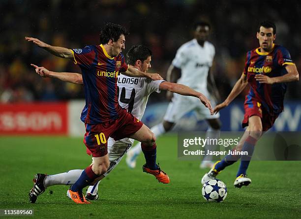 Lionel Messi of Barcelona duels for the ball with Xabi Alonso of Real Madrid during the UEFA Champions League Semi Final second leg match between...