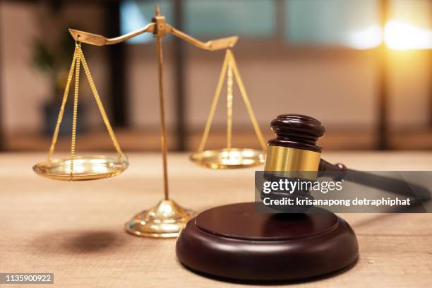 justice scales and books and wooden gavel - justizsystem stock-fotos und bilder