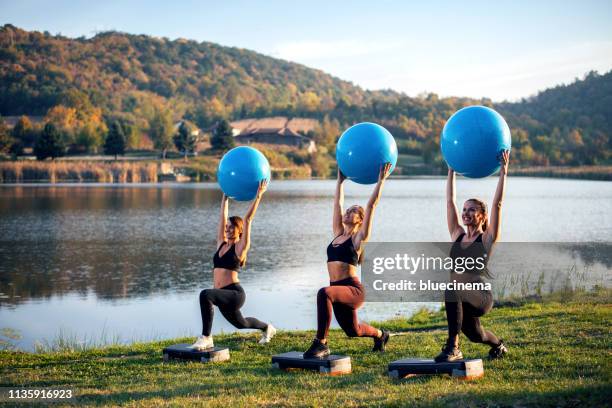 las mujeres ejercitan junto al lago con la pelota. - yoga ball fotografías e imágenes de stock