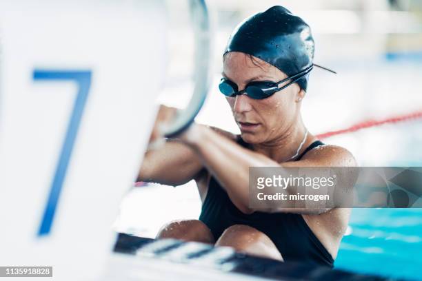 mid adult woman swimming in pool - swimming stock-fotos und bilder