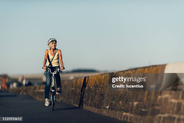 senior woman rijden fiets op fietspad - folding bike stockfoto's en -beelden