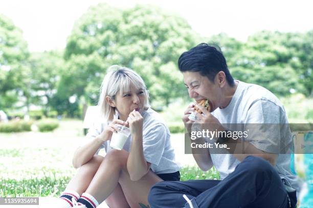 happy couple eten lunch in het park - blond women happy eating stockfoto's en -beelden