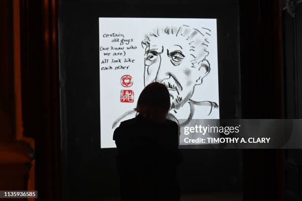 Woman looks at "Self-Portraits, 2003-2016, 2017" a projection part of two hundred and twenty drawings documenting Leonard Cohens self-portraits...