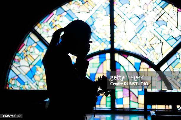 silhouette woman crying against stained glass - trauerzeit stock-fotos und bilder
