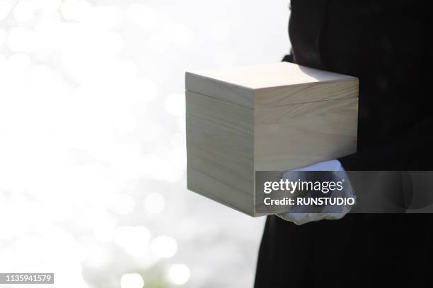mourner holding urn - feuerbestattung stock-fotos und bilder