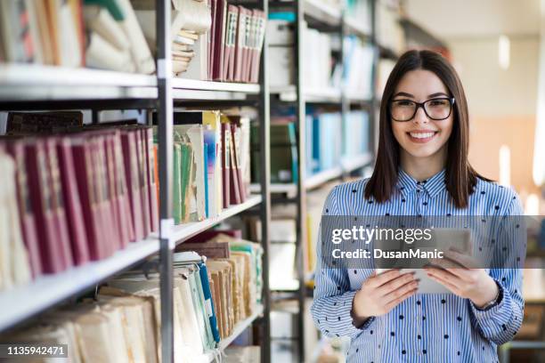 portrait of a gorgeous student using a tablet computer in a library - online library stock pictures, royalty-free photos & images