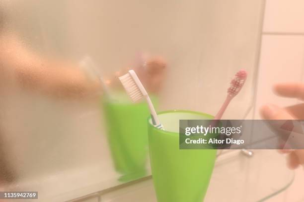 a man's hand is going to take a  toothbrush. - mirror steam stockfoto's en -beelden