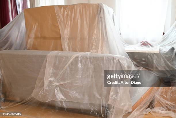 plastic covering furniture and belongings in a living room. - plastic design furniture stockfoto's en -beelden