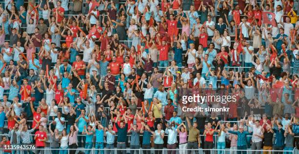 group of spectators cheering in stadium - red sports jersey stock pictures, royalty-free photos & images