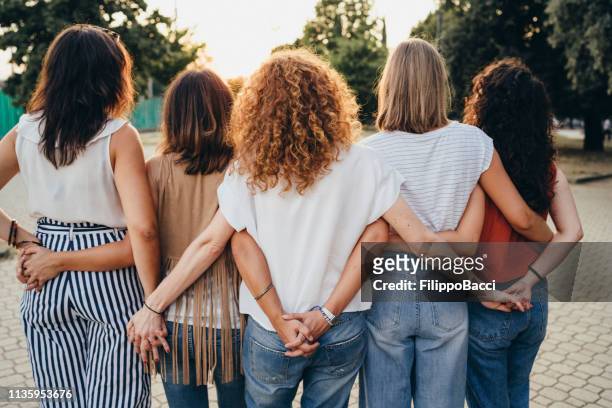 groupe d'amis de femmes retenant des mains ensemble contre le coucher du soleil - femmes de dos enlacée photos et images de collection