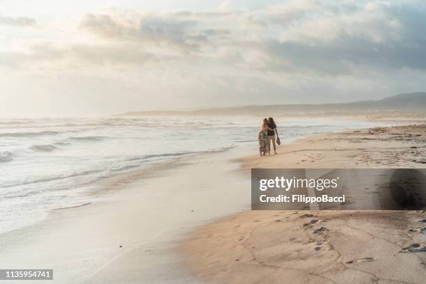 young adult couple walking on the beach together - beach footprints stock pictures, royalty-free photos & images