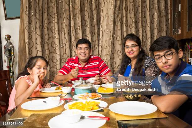 happy family eating together at home - indian family dinner table stock pictures, royalty-free photos & images