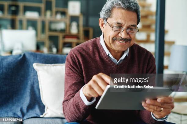 keeping up with what's hip and happening - mature man using digital tablet stock pictures, royalty-free photos & images