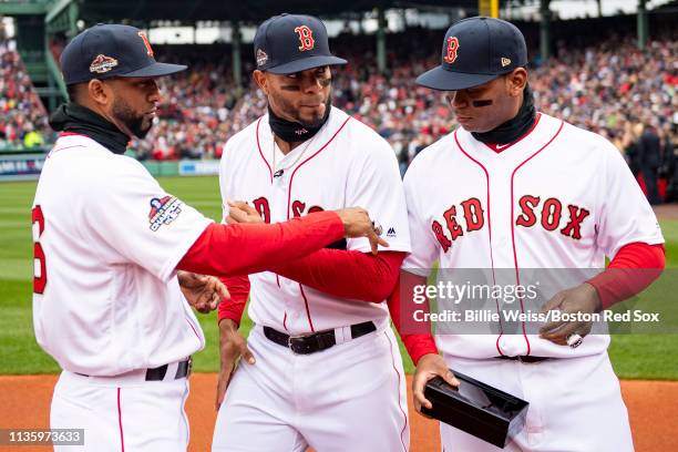 Eduardo Nunez, Xander Bogaerts, and Rafael Devers of the Boston Red Sox look at their rings during a 2018 World Series championship ring ceremony...