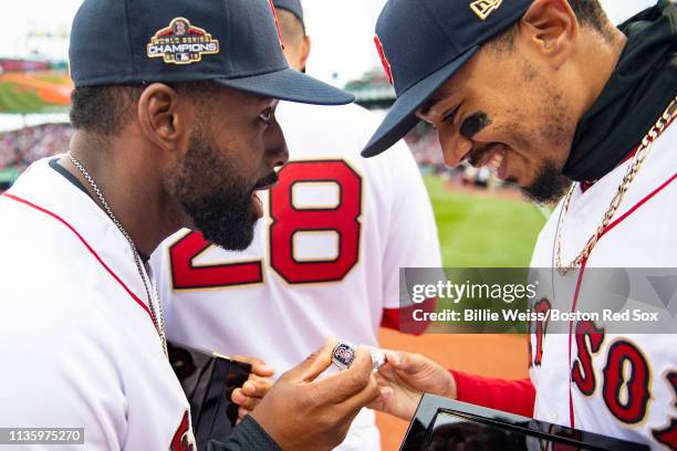 Jackie Bradley Jr. And Mookie Betts of the Boston Red Sox look at their rings during a 2018 World Series championship ring ceremony before the...