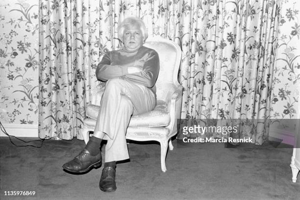 Photo of British film director Ken Russell as he sits in an armchair, New York, New York, 1980.