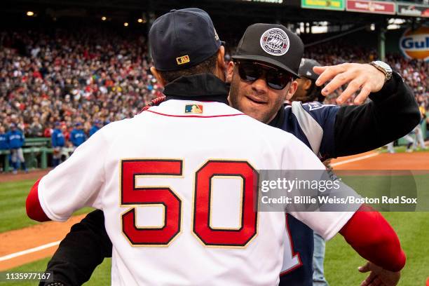 Mookie Betts of the Boston Red Sox reacts with Julian Edelman of the New England Patriots during a 2018 World Series championship ring ceremony...