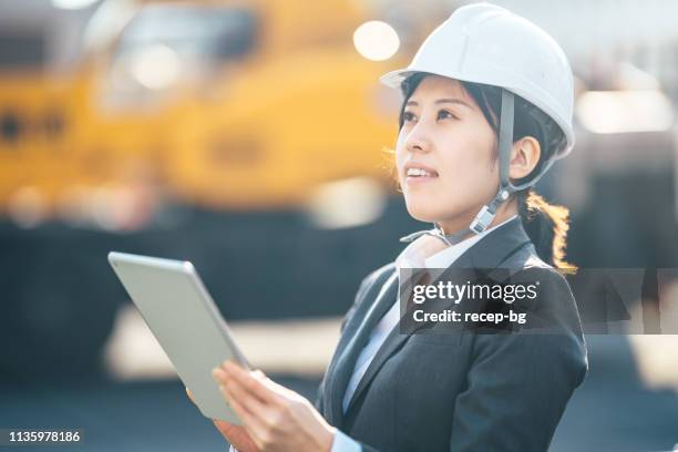 junge frau mit digitalem tablet auf baustelle - person in suit construction stock-fotos und bilder