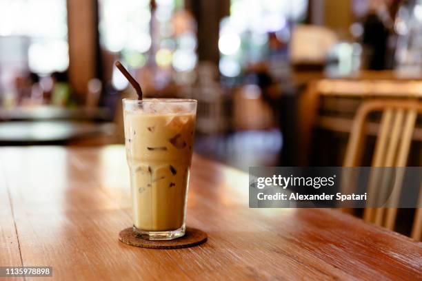 glass of iced coffee on the table in a coffee shop - cafe latte stockfoto's en -beelden